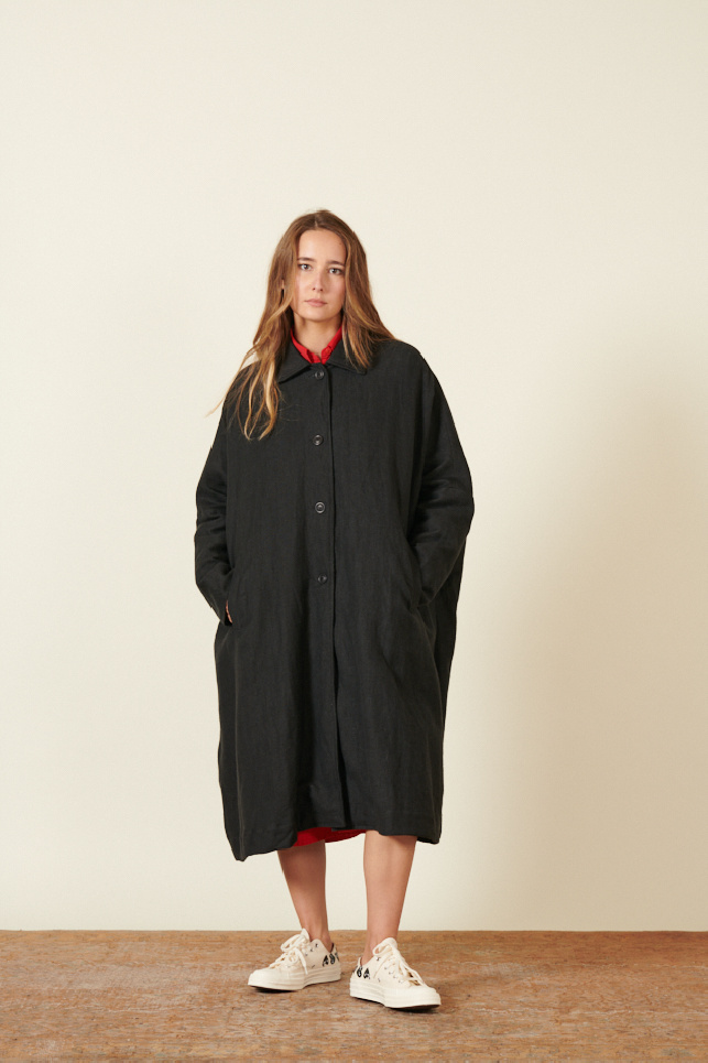 manteau noir, coupe longue et ample, avec emmanchures basses